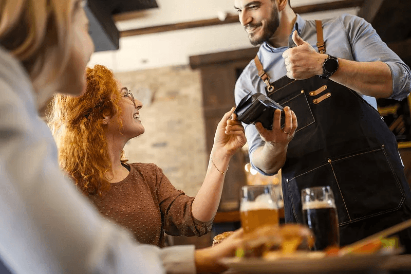 Server helping guests complete payment at their table