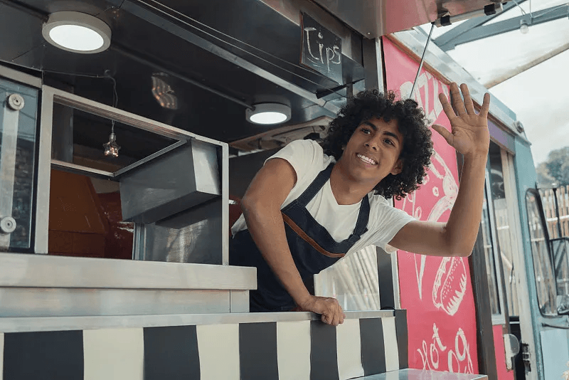 A food truck team member serving customers from the truck window