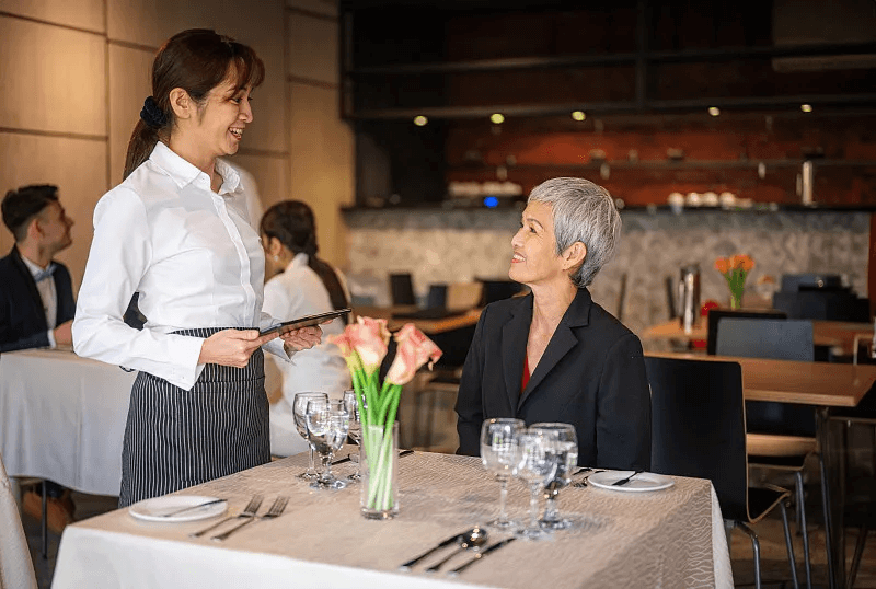 A server providing attentive service to a guest at a restaurant table