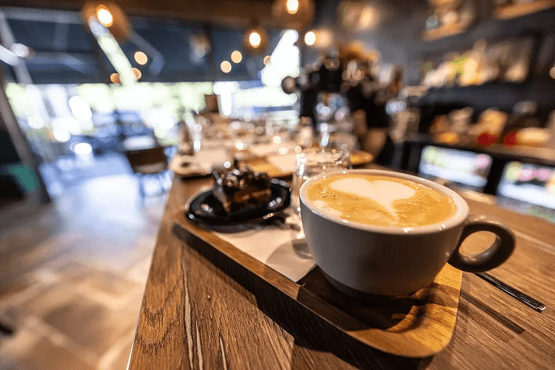 A prepared cup of coffee on the counter inside a busy cafe