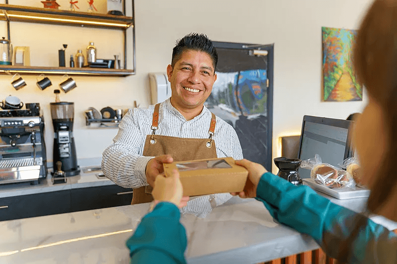 A takeaway team member handing a packed order to a customer