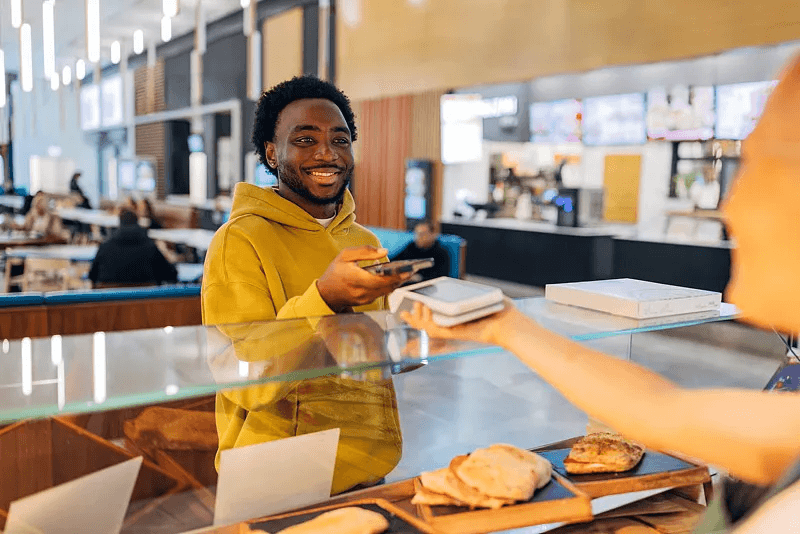 A customer presenting a phone while collecting a takeaway order